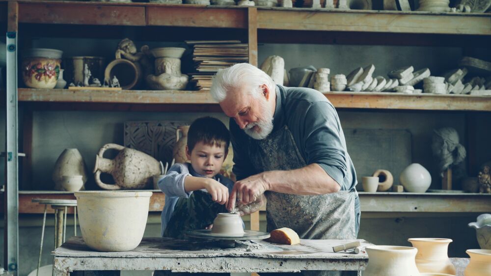 oudere man met een kind aan het potten bakken
